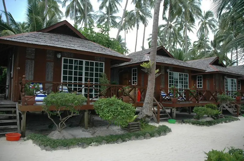 Standalone Chalets at Sipadan-Mabul Resort: timber chalets on stilts with verandahs, on the sand beneath coconut palms